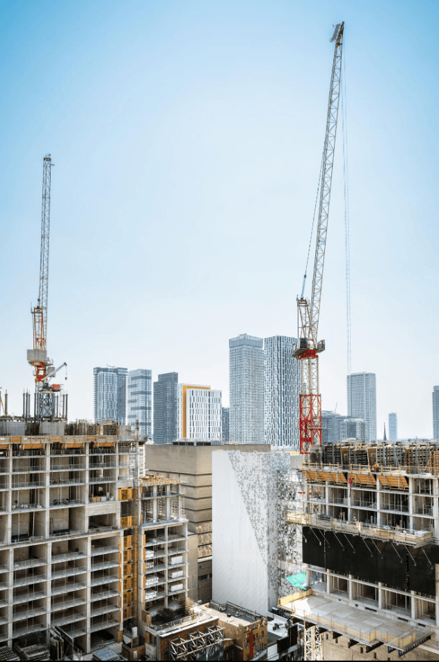 Tower cranes above high-rise buildings under construction in a city skyline